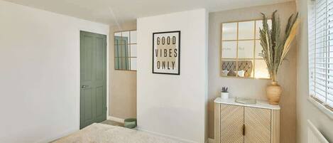 A bedroom with a bed, a green door, a wall-mounted cabinet, and a framed sign.