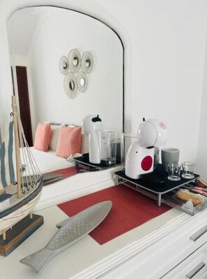 Ein modernes Hotelzimmer mit einem Bett, einem kleinen Tisch mit Wasserkocher, Gläsern und einer Speisewagenplatte mit Essen.