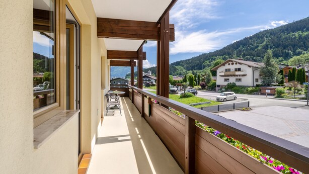 Ein Balkon mit Holzbalkonen, Blick auf einen Parkplatz und ein Berg im Hintergrund.