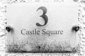 A metal plaque with the number 3 and the text "Castle Square" mounted on a wall. - Castle Square - 2 Bedroom - Mumbles (Swansea)