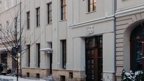 Fachada de hotel de estilo arquitectónico clásico, con una escultura destacada en el segundo piso, una gran entrada en arco y un letrero que indica el nombre del hotel.