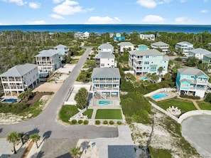 A coastal residential area with multiple two-story houses, a central road, and a clear view of the ocean. - Pet-Friendly Retreat with Pool (Cape San Blas)