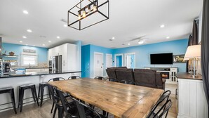 A modern kitchen with white cabinets, a wooden dining table, and black chairs.