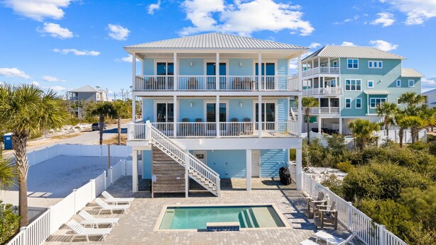 Ein mehrstöckiges Strandhaus mit Pool, Balkonen und einer Treppe zu den oberen Ebenen.