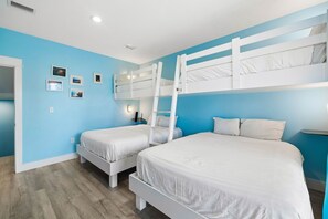 A room with two bunk beds, a ladder, a bedside table, and wall-mounted lights. - Pet-Friendly Retreat with Pool (Cape San Blas)