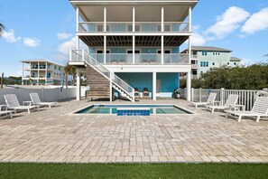 A two-story building with a pool, outdoor seating, and a staircase leading to the upper level. - Pet-Friendly Retreat with Pool (Cape San Blas)
