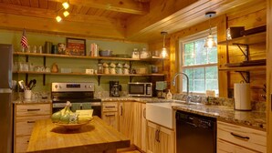 A cozy kitchen with wooden cabinets, a granite countertop, a stainless steel oven, a microwave, and a sink.