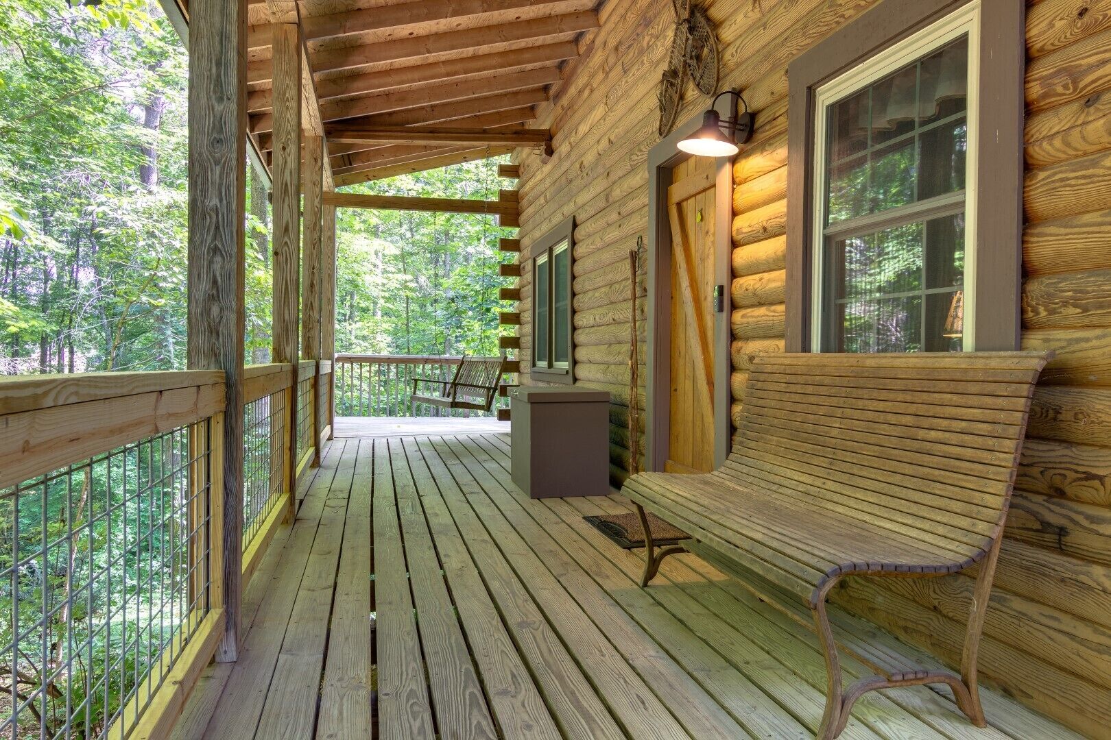 A wooden cabin with a porch, a bench, and a window.