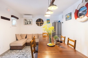 A dining area with a wooden table, chairs, a vase with flowers, and a refrigerator.