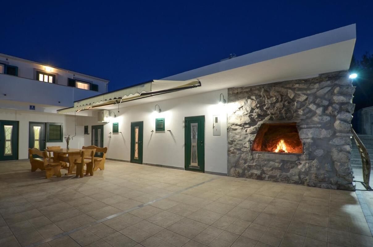 A building with a stone fireplace, a covered outdoor seating area, and a staircase leading to an upper level.