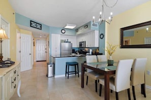 A kitchen with white cabinets, a refrigerator, and a dining area with a table and chairs.