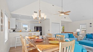 Un vaste espace de vie comprenant une table à manger en bois, un canapé bleu et un ventilateur de plafond.