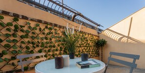 A round table with a white top, two chairs, a potted plant, and a book. - Terrazza Relax a Borgo Dora by Wonderful Italy (Turin)