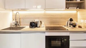 A modern kitchen with a built-in microwave, a kettle, and a coffee maker on the countertop. - Largo Pannonia Home: A Gateway to Historic Rome Near the Colosseum and St. John & more (Roma)