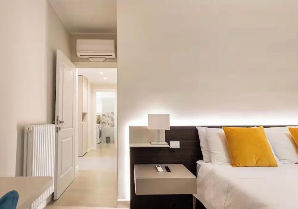 Une chambre d’hôtel avec un lit, une table de chevet, une lampe et une vue sur le couloir.