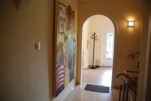 Un couloir orné d’une fresque murale, avec un porte-manteau et un escalier.