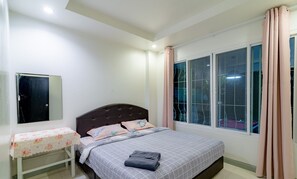 Um quarto com cama, mesa de cabeceira, janela com cortinas e porta.
