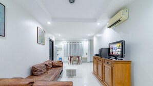 Una sala de estar moderna con un sofá de cuero marrón, un mueble de madera y un televisor.