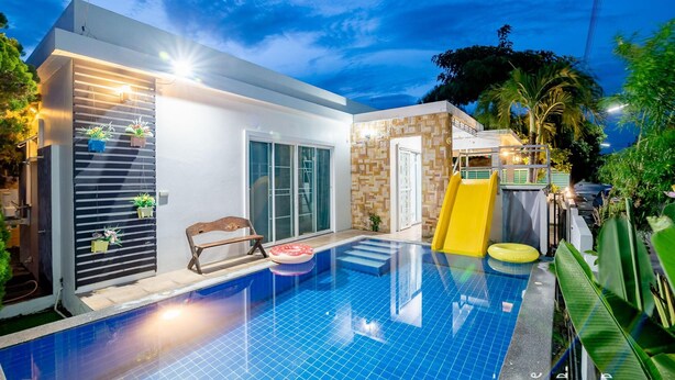 Una casa moderna con piscina, tobogán y banco.