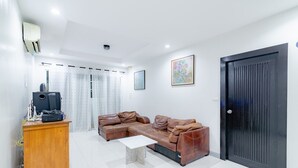 Una sala moderna con un sofá de cuero marrón, un mueble de madera y una puerta negra.