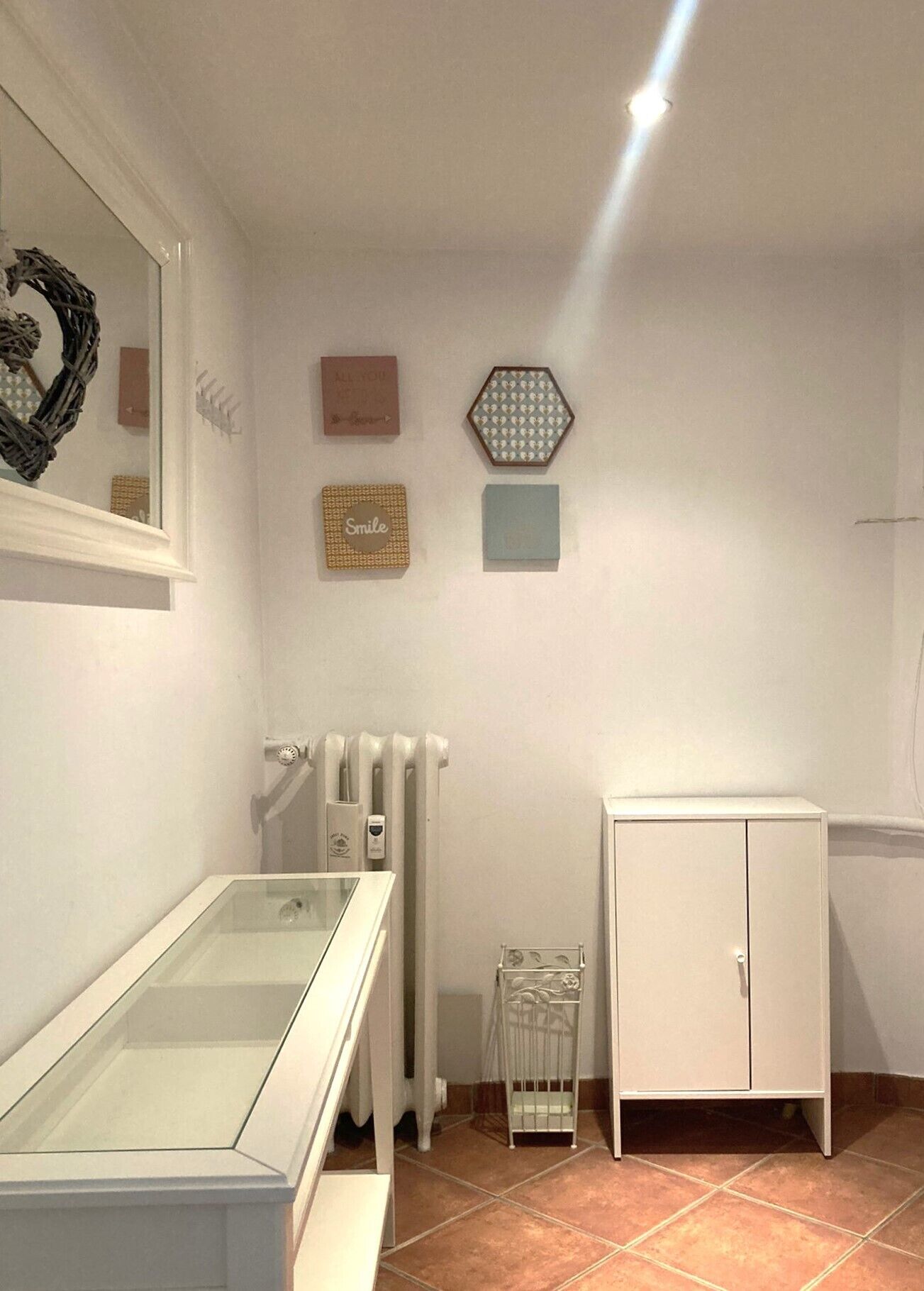 A clinical room with a glass cabinet, a white cabinet, a radiator, and wall decorations.