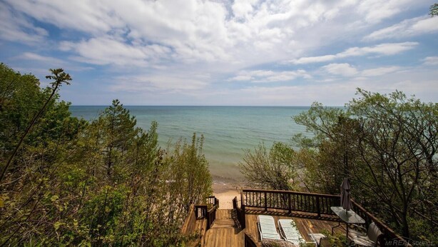 A wooden deck with lounge chairs overlooking a beach. - Waterfront Homes in Lexington  (Lexington)