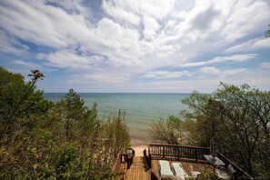 A wooden deck with lounge chairs overlooking a beach.
