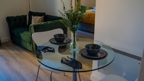 Uma mesa de jantar com tampo de vidro, um vaso de flores, duas tigelas e talheres.