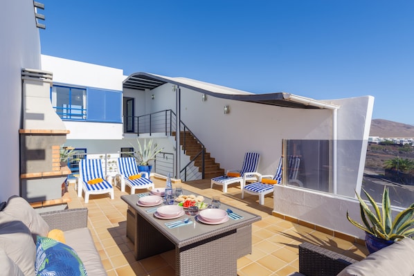 A terrace with outdoor furniture, a dining table set, and a staircase leading to an upper level.