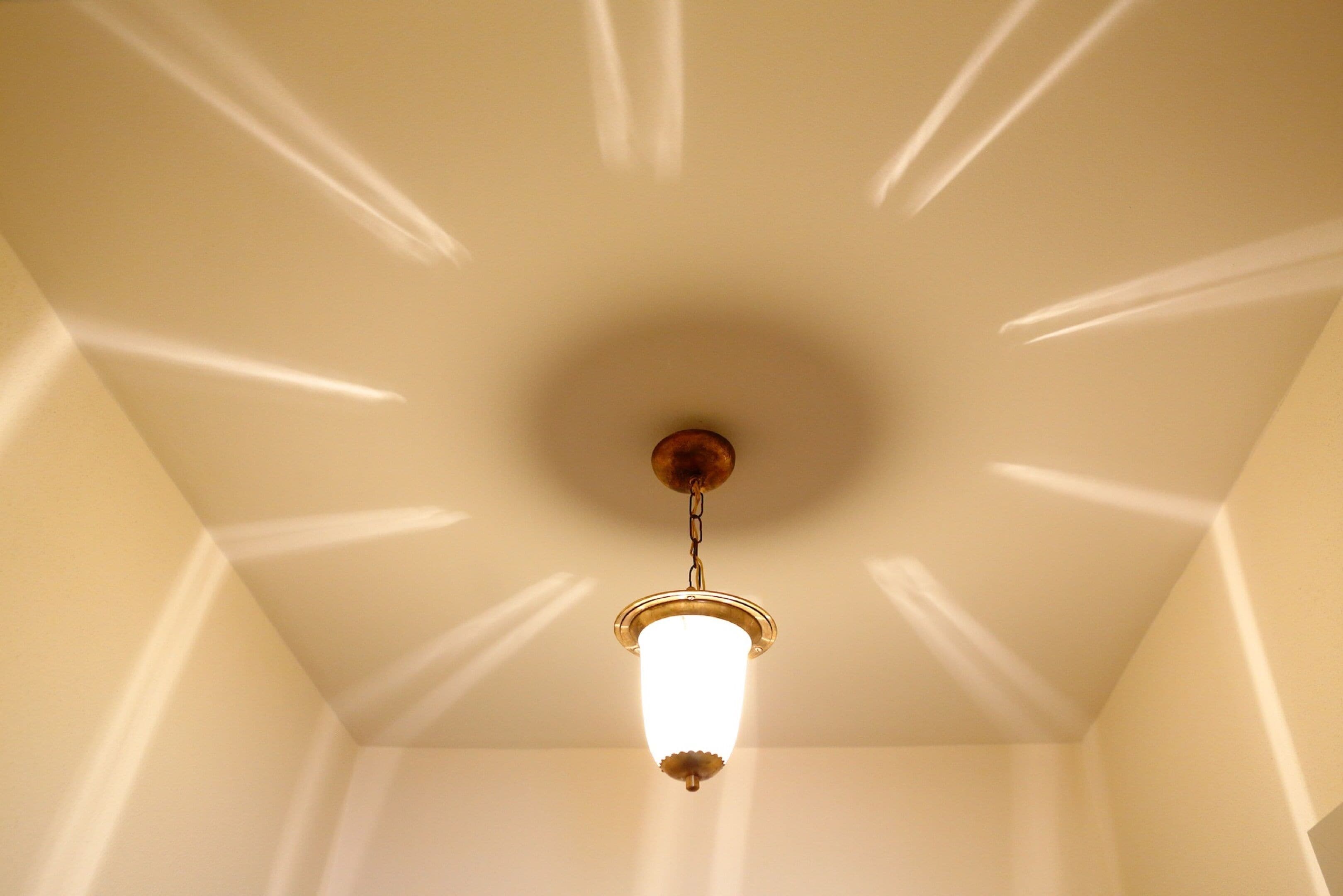 A ceiling with a single light fixture casting shadows.