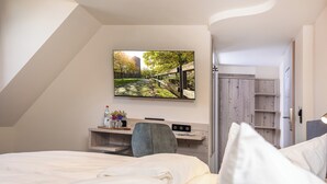Habitación de hotel moderna con una cama, un escritorio y un televisor instalado en la pared que muestra una vista panorámica.