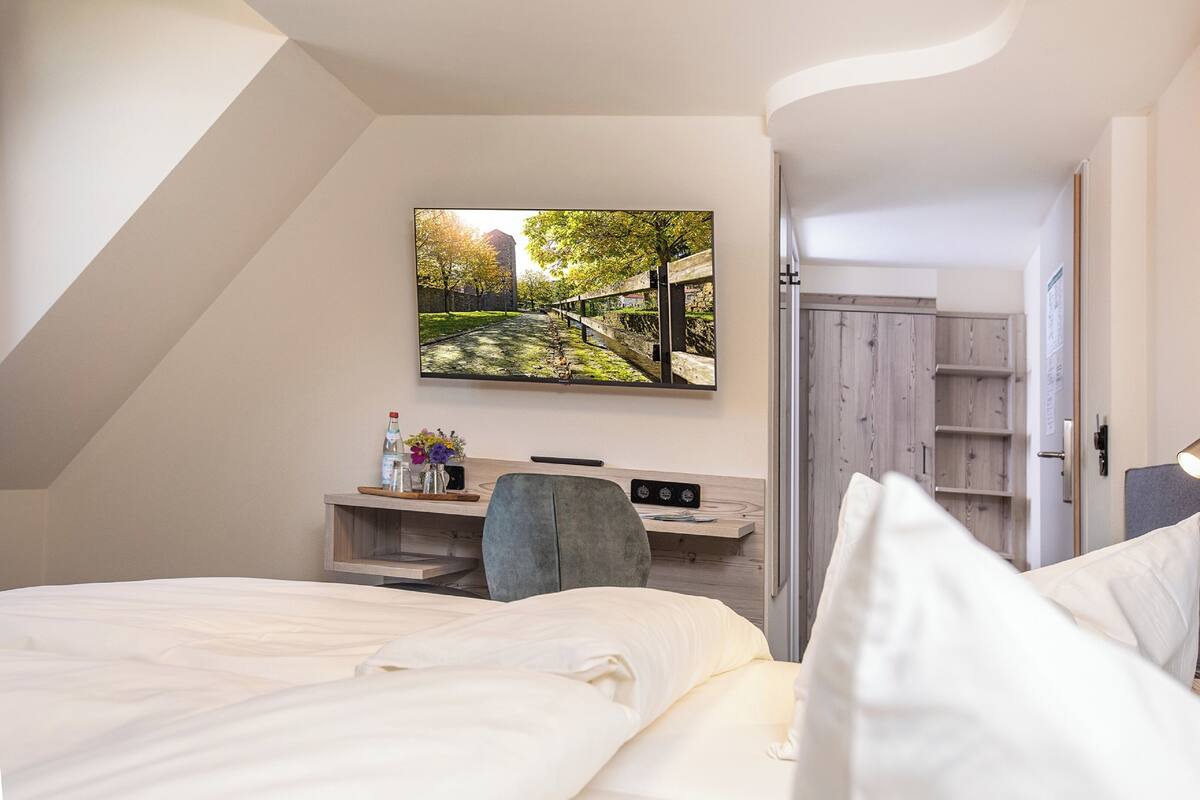 Een moderne hotelkamer met een bed, een bureau en een tv aan de muur, waarop een mooi uitzicht te zien is.