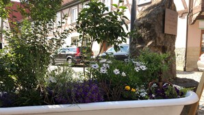 Una jardinera con flores en una calle adoquinada, con un edificio al fondo.