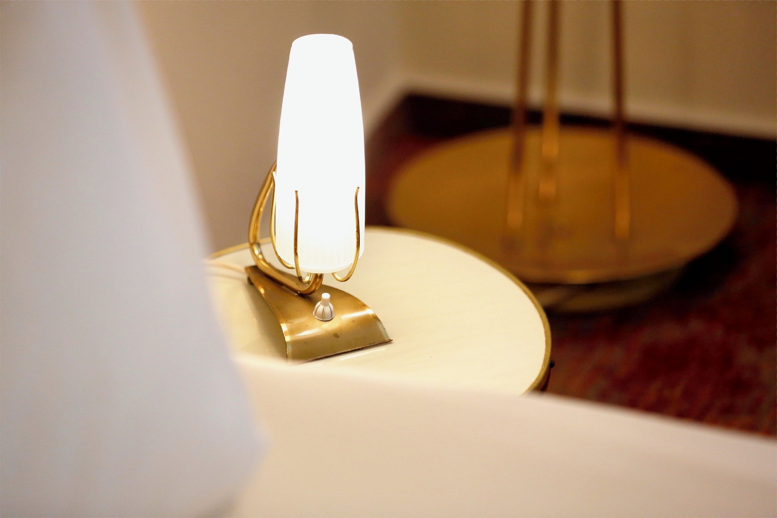A close-up of a white table with a gold-colored lamp on it.