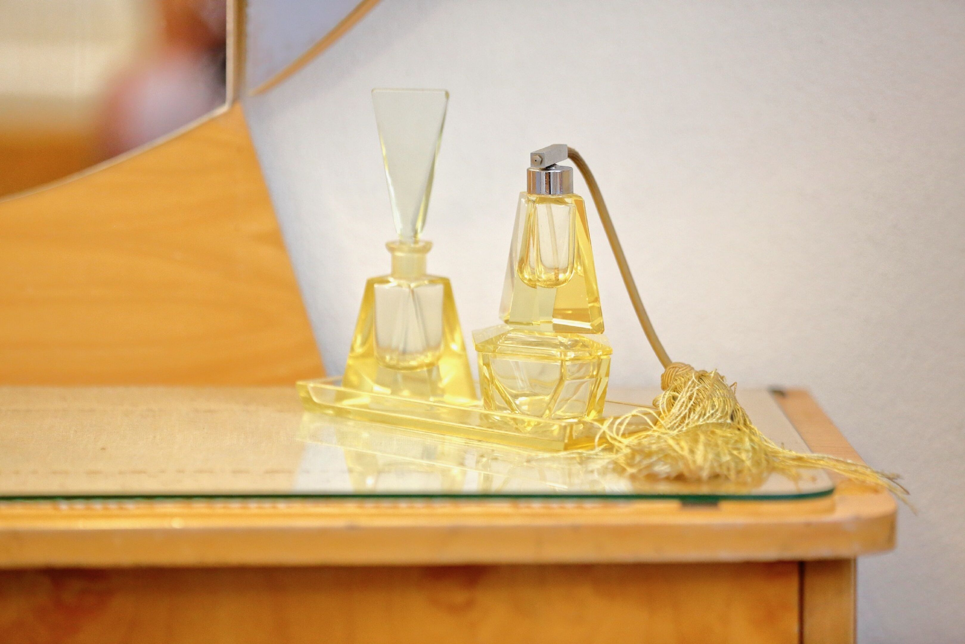 Two perfume bottles on a wooden surface with a glass tray.