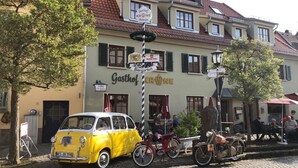 Un coche amarillo antiguo estacionado frente a un edificio con un letrero que dice "Gasthof KRONE".