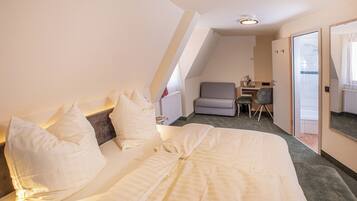 A bedroom with a large bed, a desk, and a chair, with a view of the outside through a door.