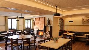 Un comedor espacioso con mesas y sillas de madera, una chimenea y un cuadro grande en la pared.