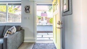 Un interior moderno con un sofá gris, una puerta amarilla y vistas al exterior.