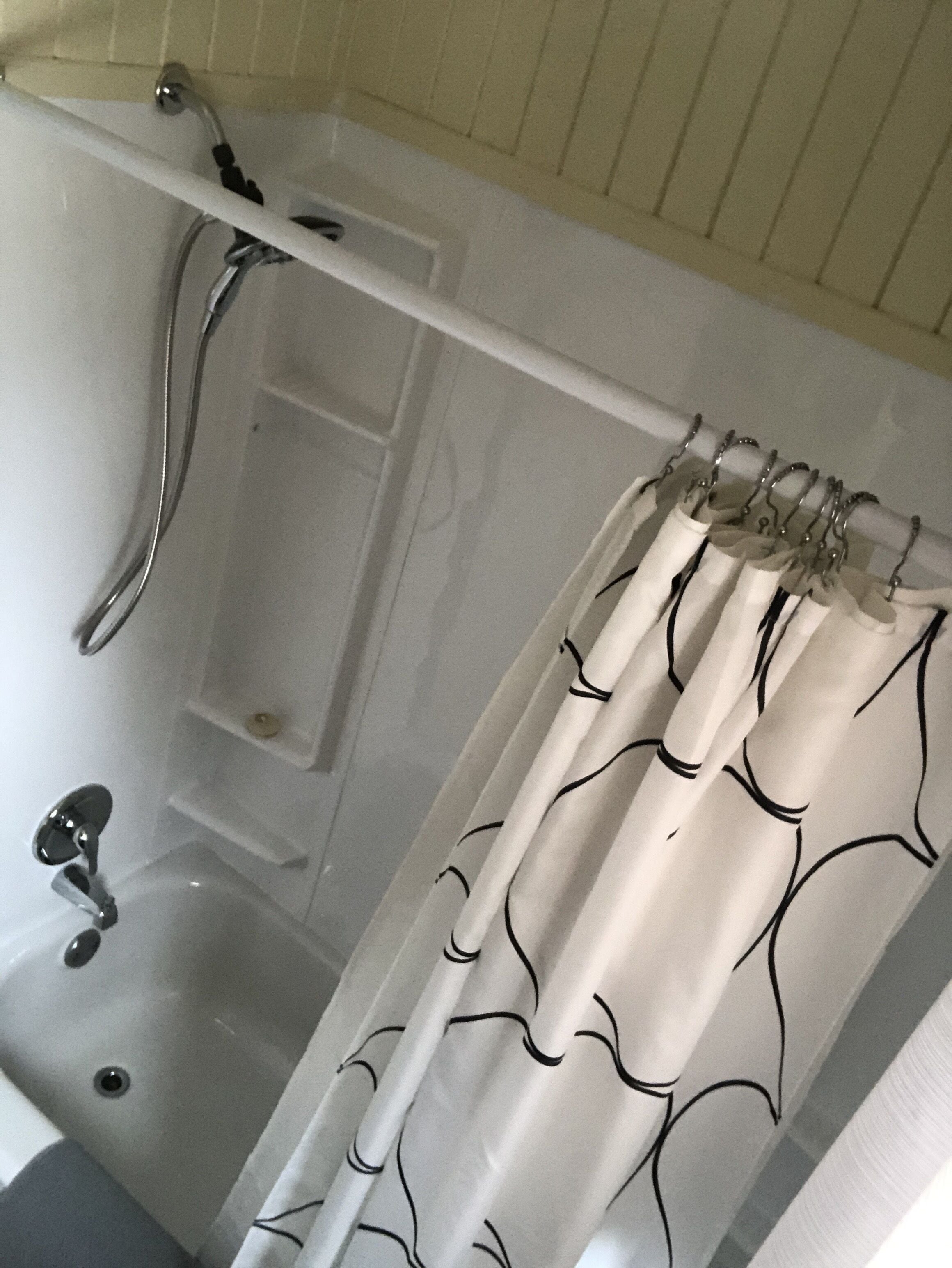 A bathtub with a showerhead, a faucet, and a shelf.