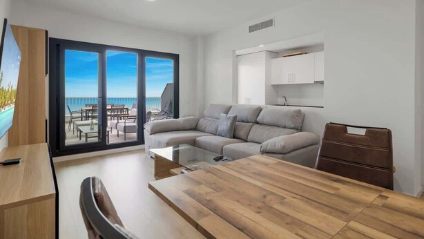 A modern living room with a large glass door leading to a balcony, a wooden dining table, and a sofa. - Panoramic Terrace w/pool by Costarentals - Ref 43 (Benalmádena)