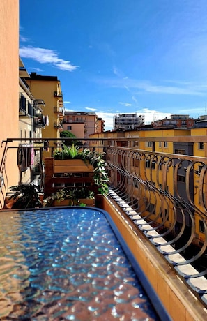 Eine Dachterrasse mit Pool, gelbe Gebäude und klarer, blauer Himmel.