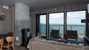 A modern living room with a sofa, chairs, a dining table, and a fireplace. - Gausta Residence (Tinn)