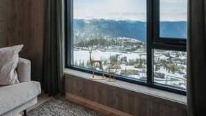 A room with a large window offering a view of a snowy landscape and mountains. - Gausta Residence (Tinn)