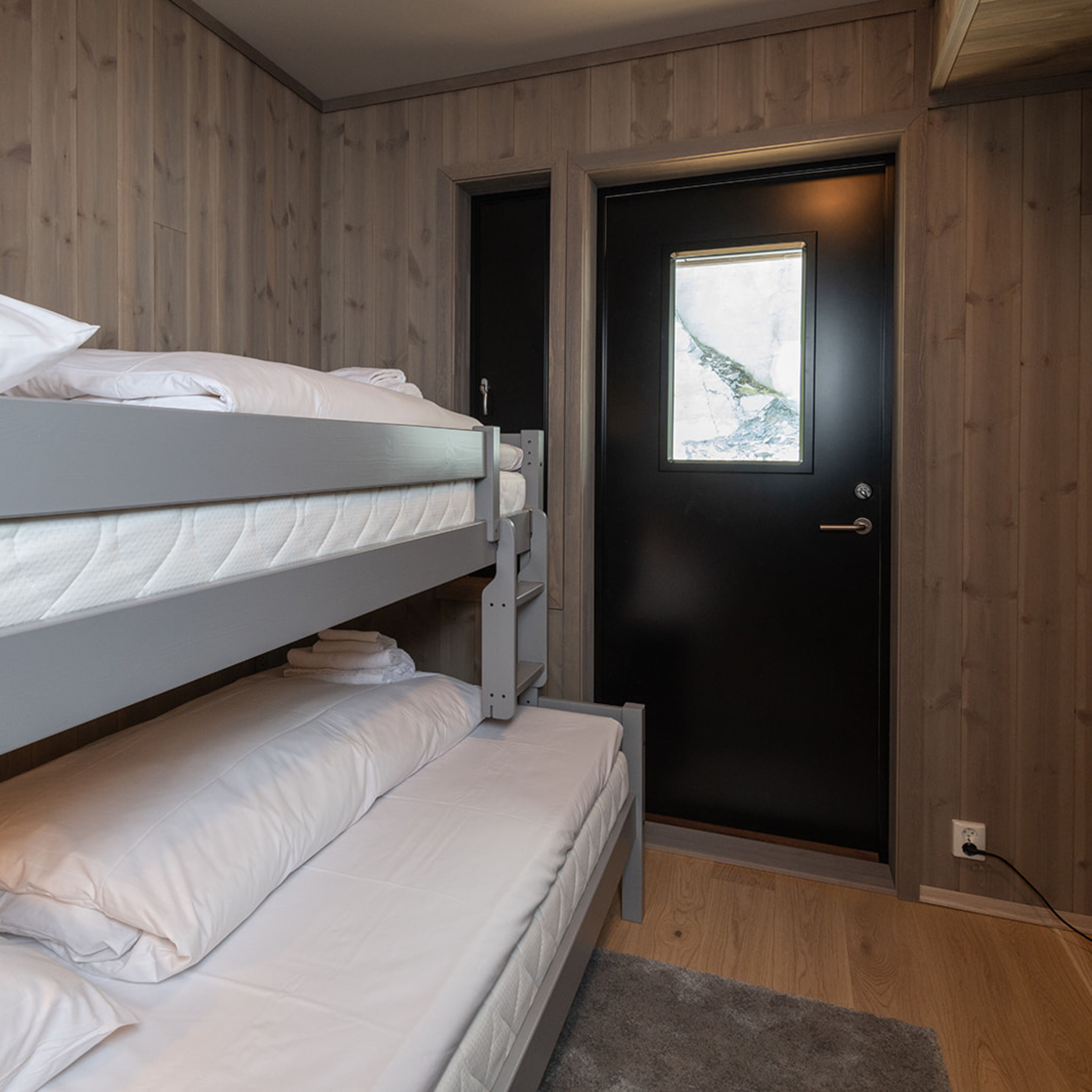 Een slaapkamer met een stapelbed, een deur en een raam.