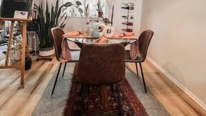 A dining area with a round table, four chairs, a hanging light fixture, and a rug.