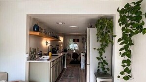 A modern kitchen with a central island, a dining area with a sofa, and a hallway leading to a living room.