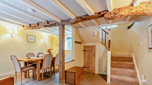 A dining area with a wooden table and chairs, a wooden bench, and a staircase leading to another level.
