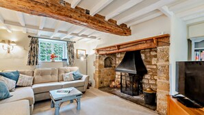 A cozy living room with a stone fireplace, a sofa, and a television.