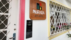 A city hostel sign with a wooden frame, a door with a metal handle, and a window with a white lattice. - Morada City Hostel (São Paulo)
